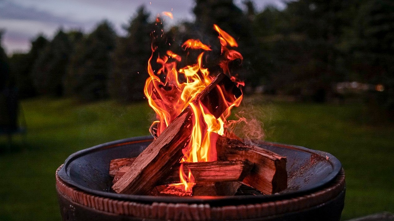 A firepit burning wooden logs in the evening.