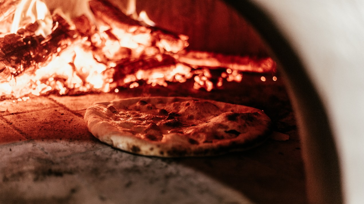 Two cooking pizzas inside a pizza oven.