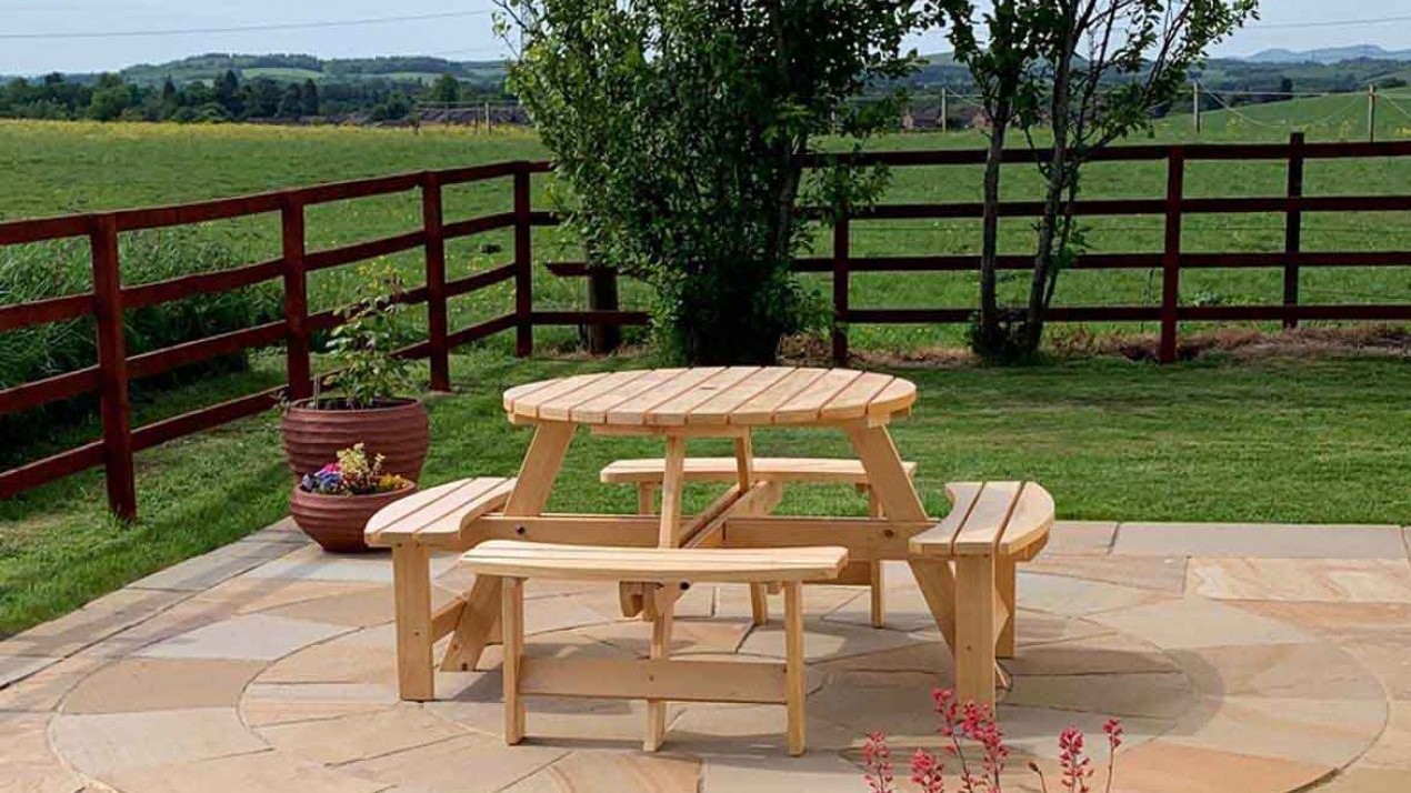 Round bench table with space for shade on the patio and lawn around it.