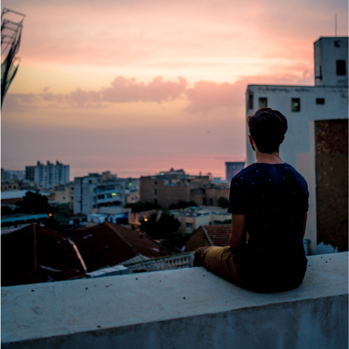 Wistfully gazing at a beautiful sunset across city skyline to the sea.