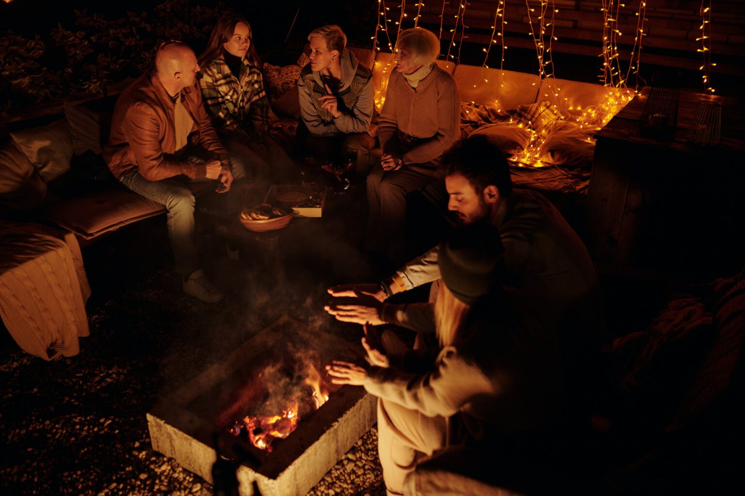 Friends seated around a firepit at night